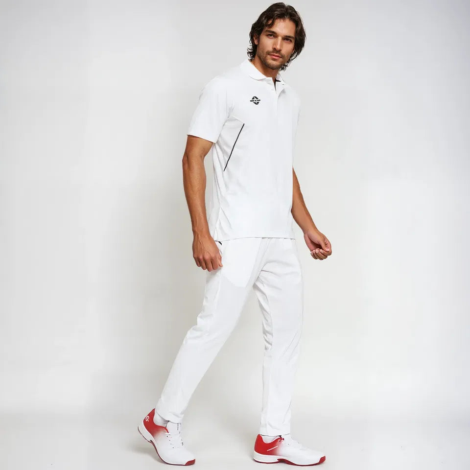 Male model wearing the off-white NIVIA Crick 1000 Jersey with half sleeves and jacquard collar, paired with matching cricket pants and white-red sports shoes, shown in a side walking pose.