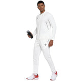 Male model wearing white NIVIA Crick 1000 cricket pants with a dotted jacquard design, paired with a matching white sports top and white-red athletic shoes, showcasing the breathable and performance-focused fit for on-field play.
