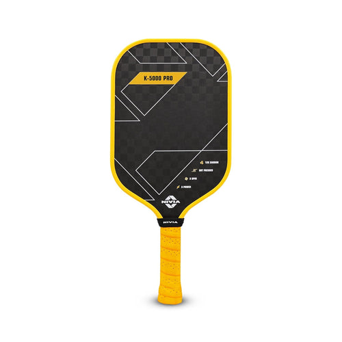 A professional NIVIA K-5000 Pro Pickleball Paddle featuring a black checkered carbon fiber face with bold yellow and white geometric accents. The paddle has a vibrant yellow edge guard and a matching perforated yellow grip. Small icons on the lower right of the face highlight technical features: 12K Carbon, Hot Pressed, X-Spin, and X-Power.