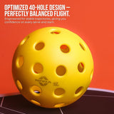 Close-up of a bright yellow NIVIA Pickleball 40 Pro Outdoor Ball with evenly spaced 40-hole design, placed on a court surface against an orange background. The NIVIA 40 Pro branding is visible on the ball. Overlay text reads: “OPTIMIZED 40-HOLE DESIGN – PERFECTLY BALANCED FLIGHT. Engineered for stable trajectories, giving you confidence on every serve and slam