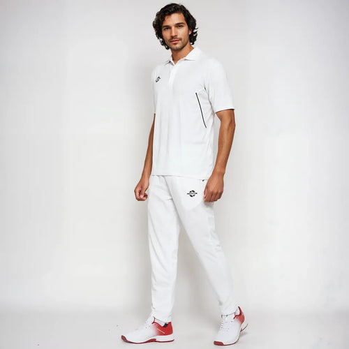 Male model wearing the NIVIA Crick 1000 Jersey in off-white, featuring a half-sleeve polyester t-shirt with jacquard collar and placket detailing, paired with matching cricket pants and white-red sports shoes