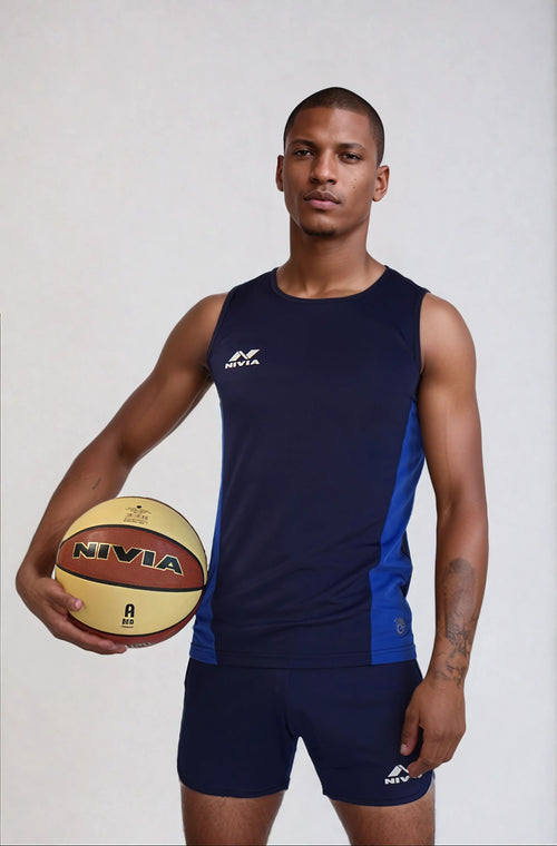 Male model wearing the NIVIA Zion Athletic Kit Track and Field Jersey Set in navy blue, featuring a sleeveless athletic top and matching shorts, holding a NIVIA basketball, showcasing functional sportswear designed for training sessions and sports activities.