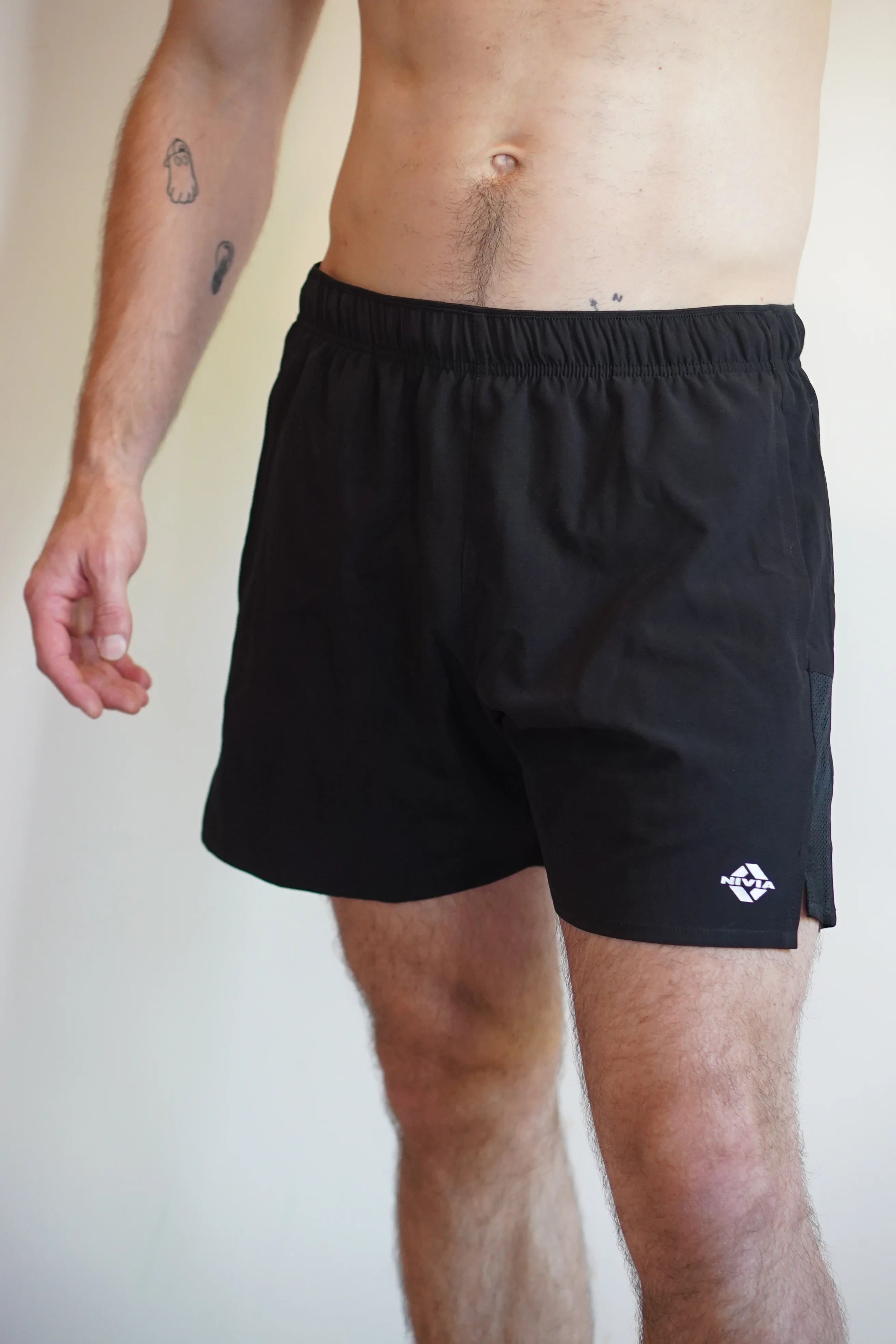Close-up view of a model wearing NIVIA Sprint Shorts in black, featuring an elastic waistband and a relaxed athletic fit suitable for training and casual wear.